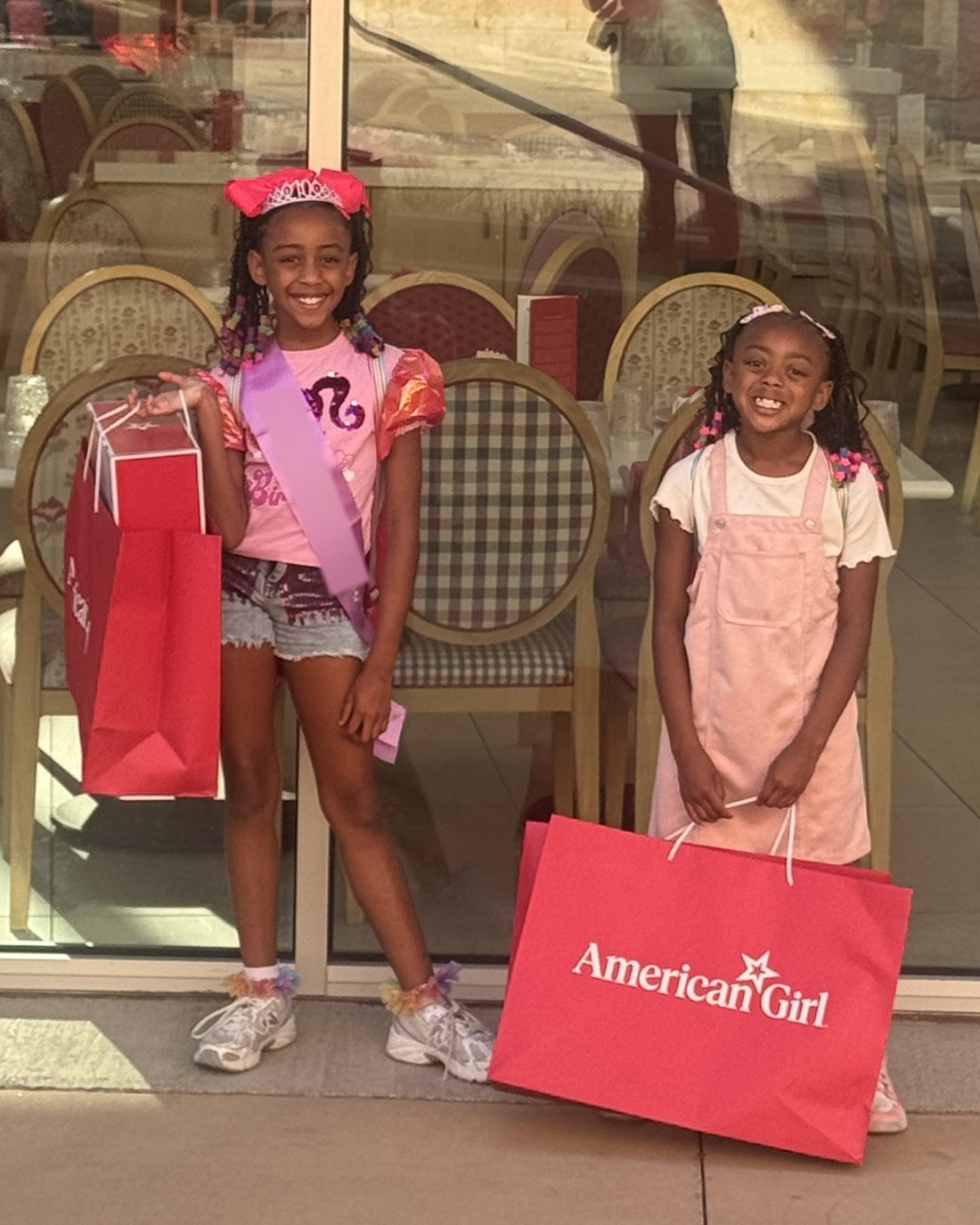 The sisters smiling with shopping bags outside a café
