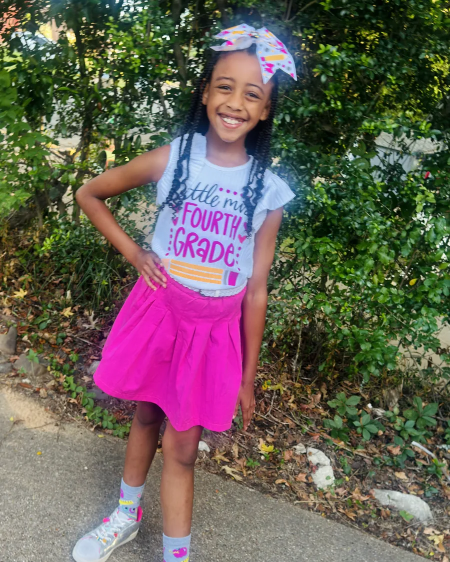 One sister posing in a pink skirt and big bow on the first day of school